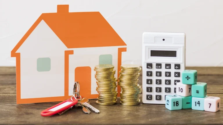 casa-llave-monedas-apiladas-calculadora-y-bloques-de-matematicas-en-la-mesa-de-madera